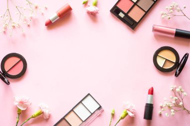 Makeup beauty products. Frame with mackeup professional cosmetic products on pink with flowers. Flat lay image with copy space.