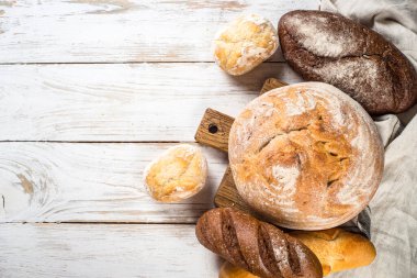 Beyaz mutfak masasında taze ekmek ve çörekler..