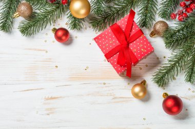 Christmas present box with red and golden holiday decorations. Top view at white wooden table.