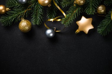 Black christmas background with fir tree and trendy golden decorations. Flat lay image with copy space.