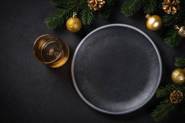 Siyah tabak ve siyah mutfak masasında tatil süslemeleri olan bir Noel masası. Kopyalama alanı olan üst görünüm.