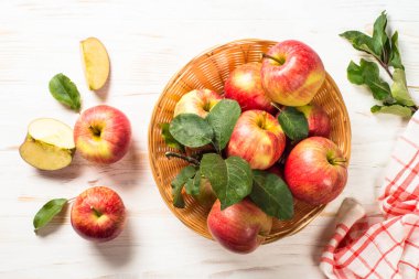 Elmalar. Beyaz ahşap masadaki sepetin içinde taze kırmızı elmalar. Üst görünüm.
