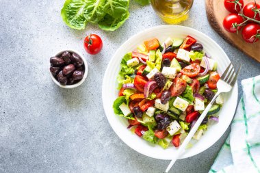 Sebzeli, zeytinli, peynirli ve zeytinyağlı sağlıklı Yunan salatası. Işık taşı masadaki en üst görünüm.