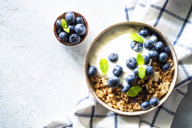Mısır gevrekli Yunan yoğurdu ve hafif taş masada taze yaban mersini. Kopyalama alanı olan üst görünüm.