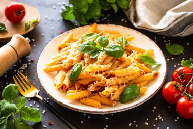 Geleneksel İtalyan makarnası, domates sosu, fesleğen ve beyaz tabakta parmesan peyniri. Kapat..