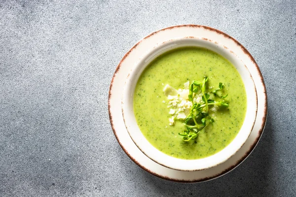 Green soup. Zucchini, spinach cream soup with cream. Healthy dish. Top view at stone table.