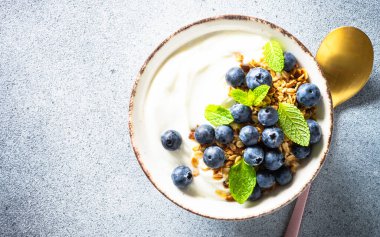 Tahıllı yoğurt ve hafif taş masada taze yaban mersini. Sağlıklı kahvaltı. Üst görünüm.