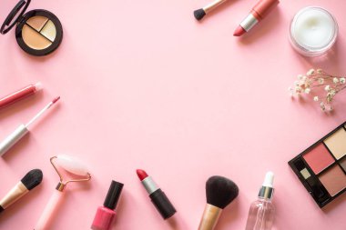 Makeup professional cosmetics on pink background. Cream, lipstick, shadow and brushes. Flat lay image with copy space.