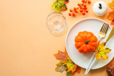 Sonbahar sofrası. Beyaz tabak, altın çatal bıçak takımı ve sonbahar süslemeleri. Kopyalama alanı olan düz resim.