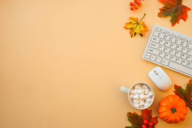 Ofis çalışma alanını boşaltın. Klavye, dizüstü bilgisayar, sonbahar bezli kupa ve sonbahar süslemeleri - balkabağı, yapraklar ve diğer.