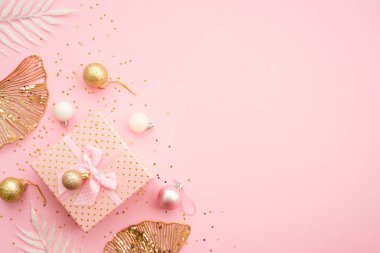 Pembe arka plandaki hediye kutusunda tatil süslemeleri var. Beyaz ve altın noel süslemeleri düz yatıyordu..