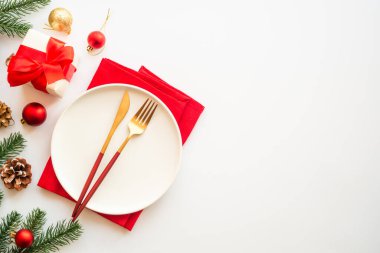 Beyaz arka planda tabak, çatal bıçak ve Noel süslemeleri olan bir Noel masası. Noel yemeği, tatil masası. Üst görünüm.