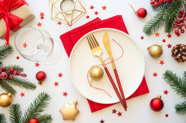 Beyaz arka planda tabak, çatal bıçak ve Noel süslemeleri olan bir Noel masası. Noel yemeği, tatil masası. Üst görünüm.