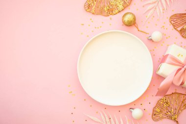 Pembe arka planda tabak, çatal bıçak ve Noel süslemeleri olan bir Noel masası. Kopyalama alanı olan düz resim.