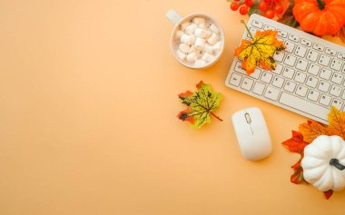 Ofis çalışma alanını boşaltın. Klavye, dizüstü bilgisayar, sonbahar bezli kupa ve sonbahar süslemeleri - balkabağı, yapraklar ve diğer.