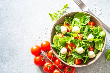 Taze yapraklı yeşil salata, domates ve mozzarella. Üst görünüm, alanı kopyala.