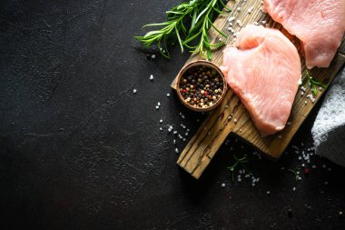 Siyah taş masadaki ahşap tahtada baharatlı ve otlu hindi bifteği. Kopyalama alanı olan üst görünüm.