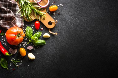 Yemek pişirme arka planı siyah taş masada. Taze sebzeler, otlar ve baharatlar. Fotokopi alanı ile pişirme malzemeleri.