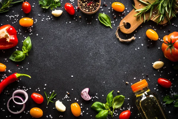 Food frame. Food cooking background on black stone table. Fresh vegetables, herbs and spices. Top view with copy space.