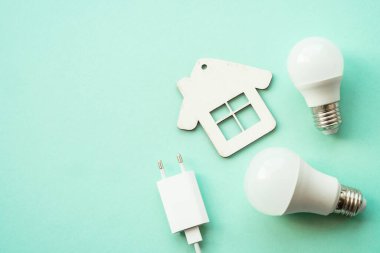 Elektrik tasarrufu. Faturaları ödüyorum. LED lamba, fişi olan kablo ve renkli arka planda ev.