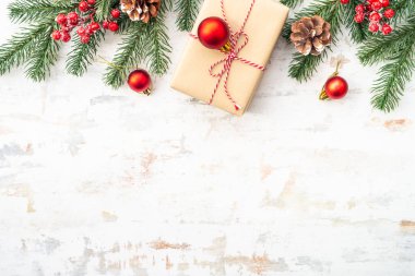 Noel arkaplanı, beyaz üzerine tatil süslemeleri. Hediye kutusu, köknar ağacı ve kırmızı takılar. Düz konum.