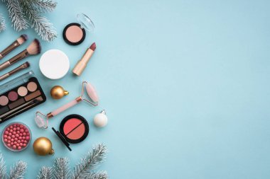 Doğal kozmetik ürünler, makyaj ürünleri ve mavi üzerine noel dekoru. Noel indirimi ve hediye konsepti. Kopyalama alanı olan düz.