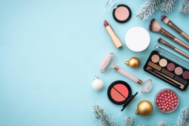 Tatil süsleriyle birlikte kış kozmetik ürünleri. Ürünleri ve Noel dekorunu maviye boyayın. Noel indirimi ve hediye konsepti. Kopyalama alanı olan düz.