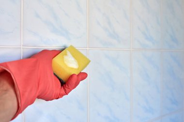 Kirli seramik fayansları temizlemek için pembe eldiven verin.