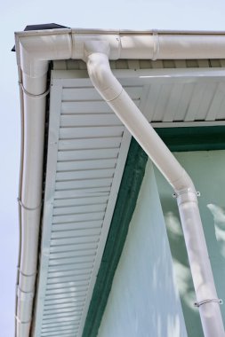 White metal rainwater pipe from the roof of the building