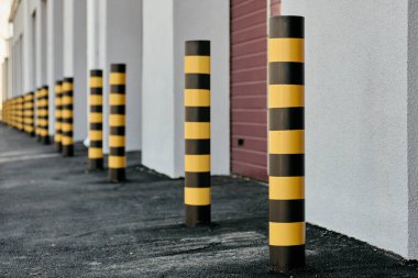 Closeup of yellow and black steel bollards that restrict movement of cars clipart