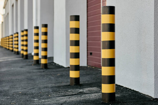 Closeup of yellow and black steel bollards that restrict movement of cars