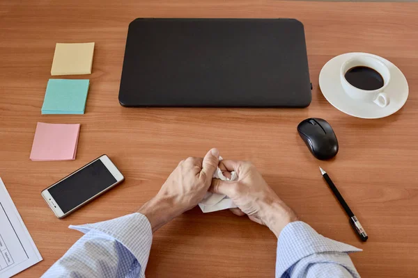 Office worker hands crumpling sheets of paper at workplace