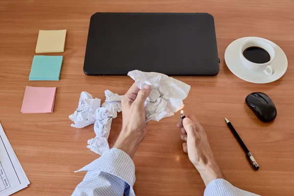 Closeup of tired manager setting fire to waste paper