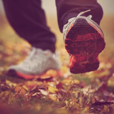 Sonbahar çimlerinde yürüyen şık spor ayakkabılı bir adam. vintage tonlama ile resim