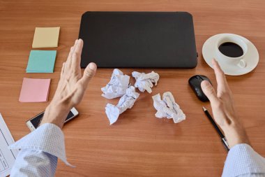 Top view of laptop, smartphone, coffee, glasses and crumpled paper on table