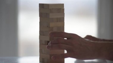 Ahşap bloklar kule oyunu oynayan adamın yakın plan fotoğrafı.