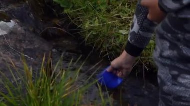 Genç çocuk içmek için Mountain Creek 'ten tatlı su topluyor.