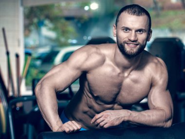 Eğitimden sonra dinlenen gülümseyen genç vücut geliştiricinin portresi, soğuk bir tonda görüntü.