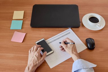 Closeup photo of businessman filling weekly time sheet. in French