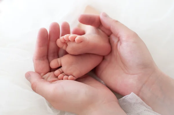Mani delle donne che tengono i piedi del bambino . — Foto Stock