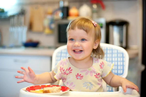 Hermosa niña riendo y comiendo en la mesa . Imágenes de stock libres de derechos