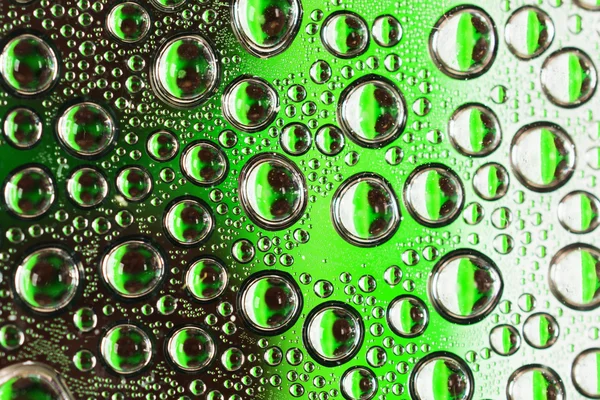 Water drops on green transparent glass