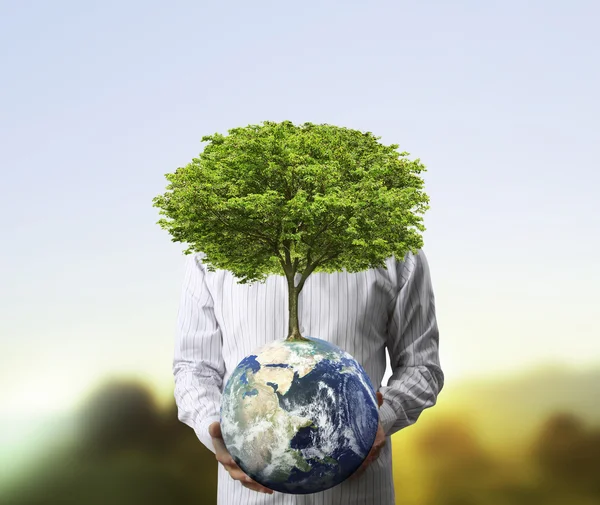 Sosteniendo un globo de tierra brillante (NASA) y un árbol en su mano — Foto de Stock