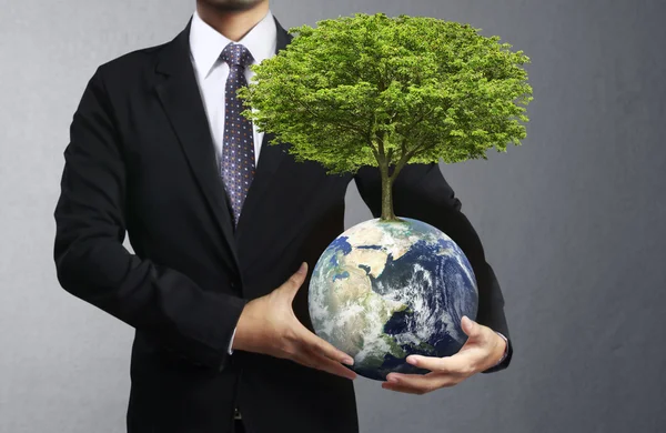 Holding a glowing earth (NASA) globe and tree in his hand — Stock Photo, Image