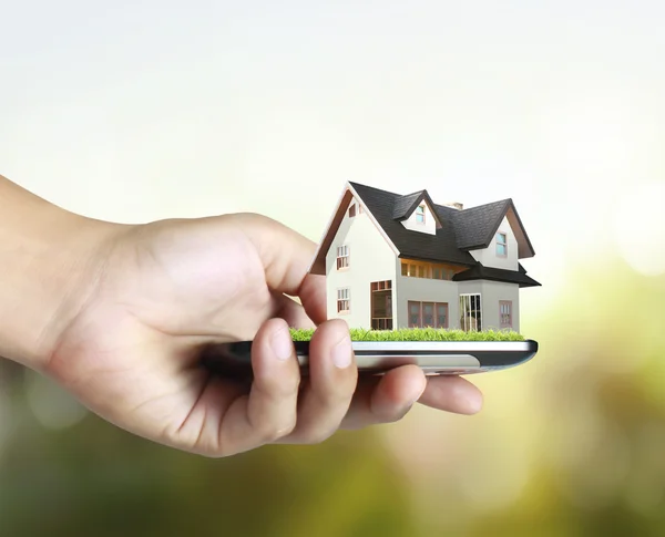 Casa en un teléfono móvil, en la mano — Foto de Stock