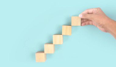 Business connecting piece of multi wood chart blocks steps in a hand