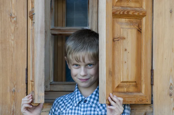 Jongen in de buurt van het houten huis — Stockfoto