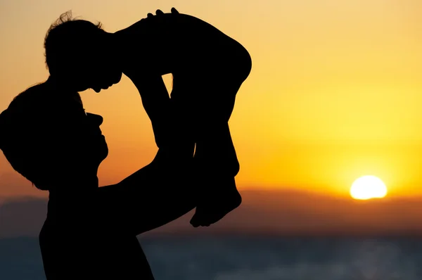 Pappa och lilla son - silhuetter på stranden vid solnedgången — Stockfoto