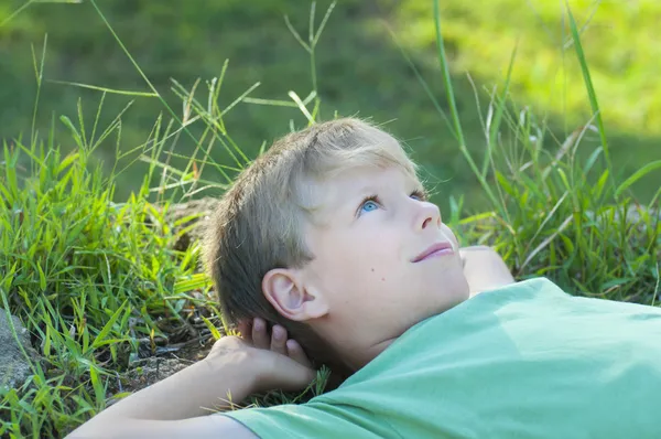 Jongen ontspannen op groen gras gazon Stockafbeelding