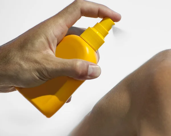 Man holding orange sun tan lotion bottle Stock Picture